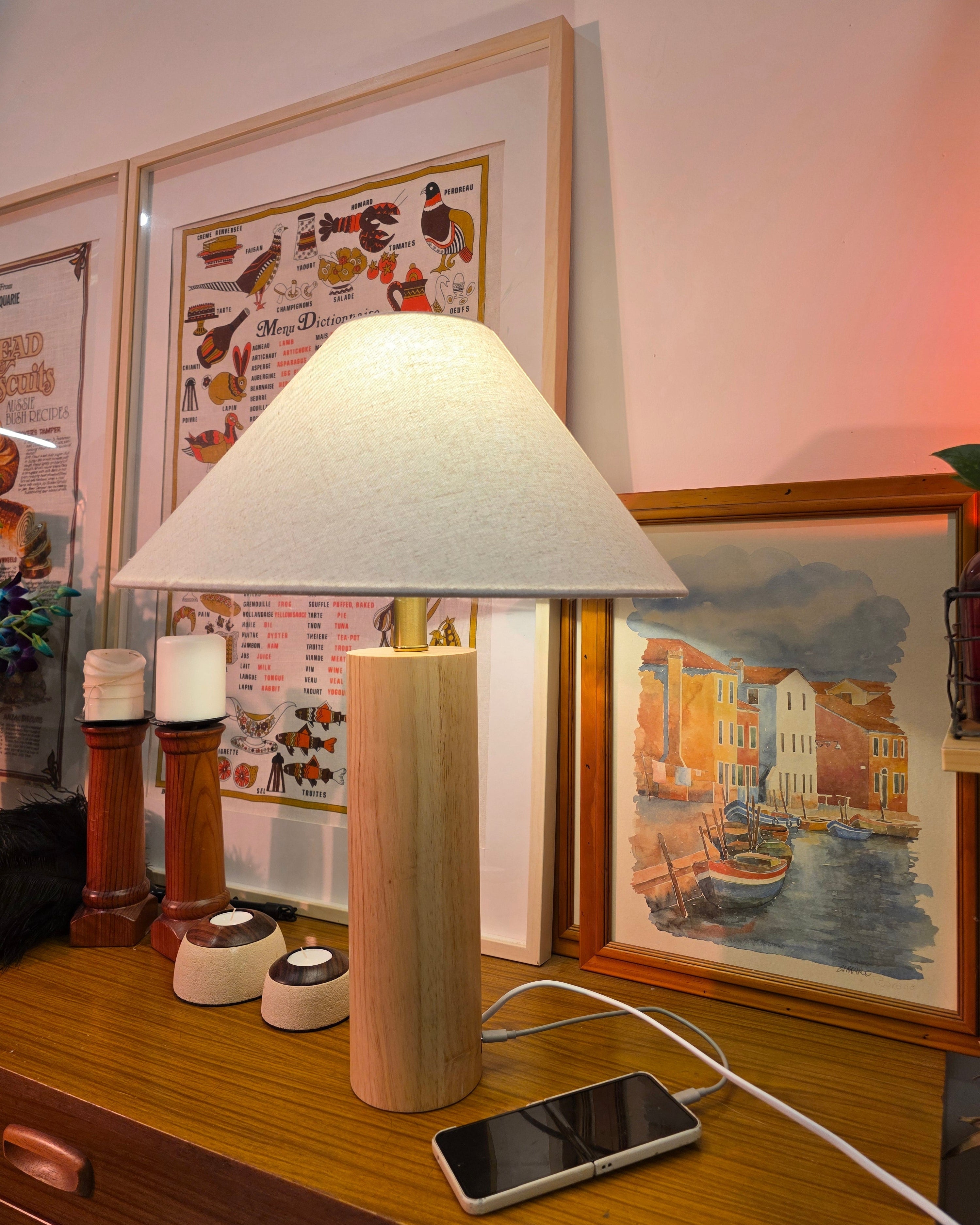 Teak wood table lamp with touch brass button and Type-C port on a desk with framed pictures and a smartphone in the background