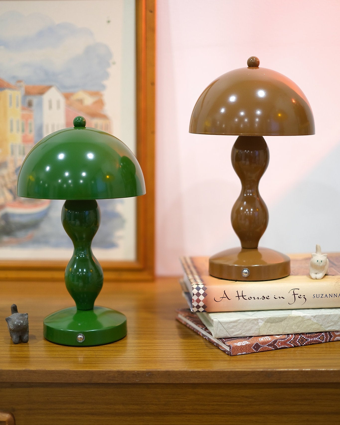 Retro mushroom lamp glowing softly in modern interior décor on a wooden surface with books and a painting in the background.