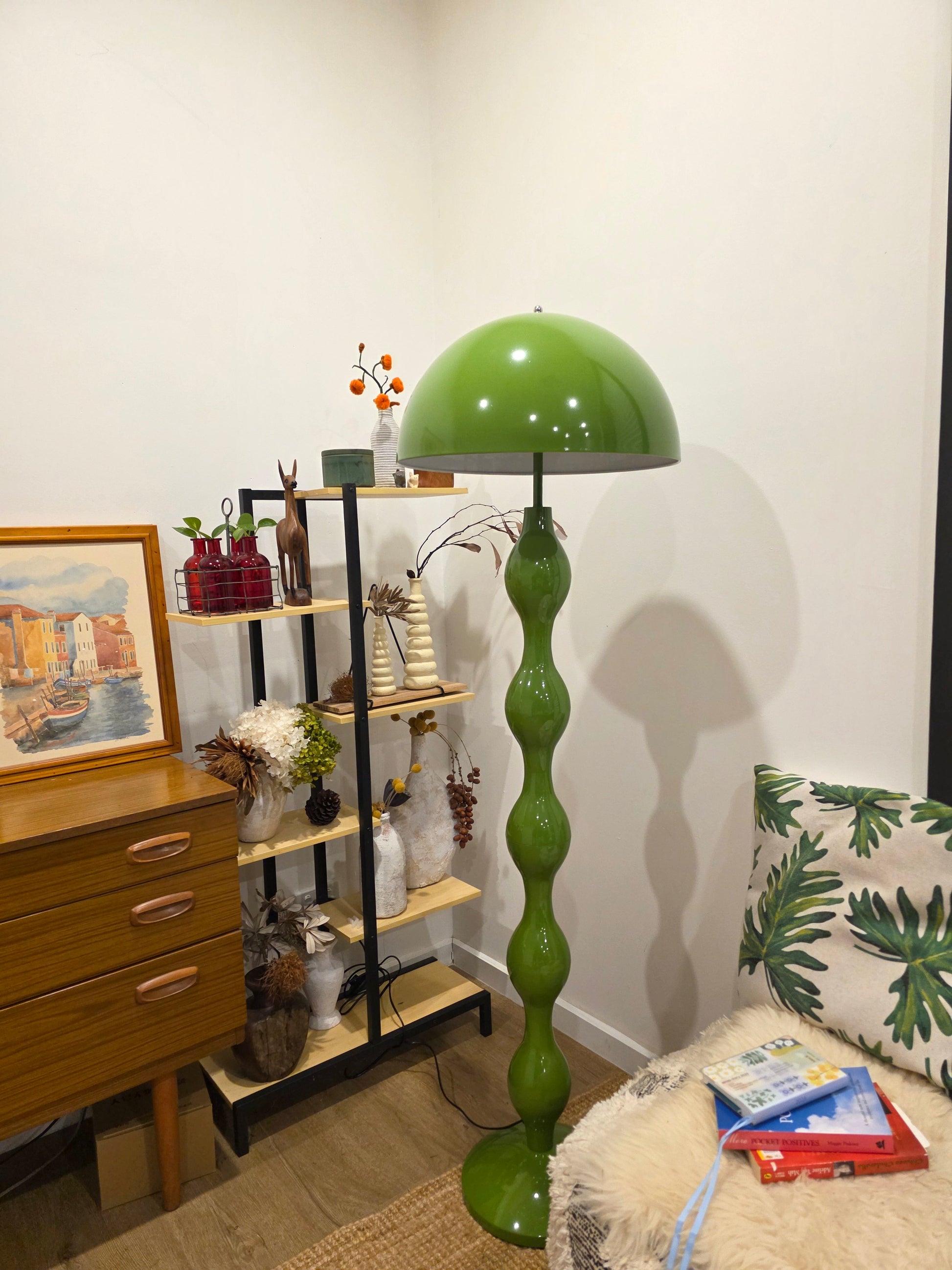 Dori Wavy Mushroom Floor Lamp in Olive Green with sculptural wavy base on a stand with decorative items in a room setting
