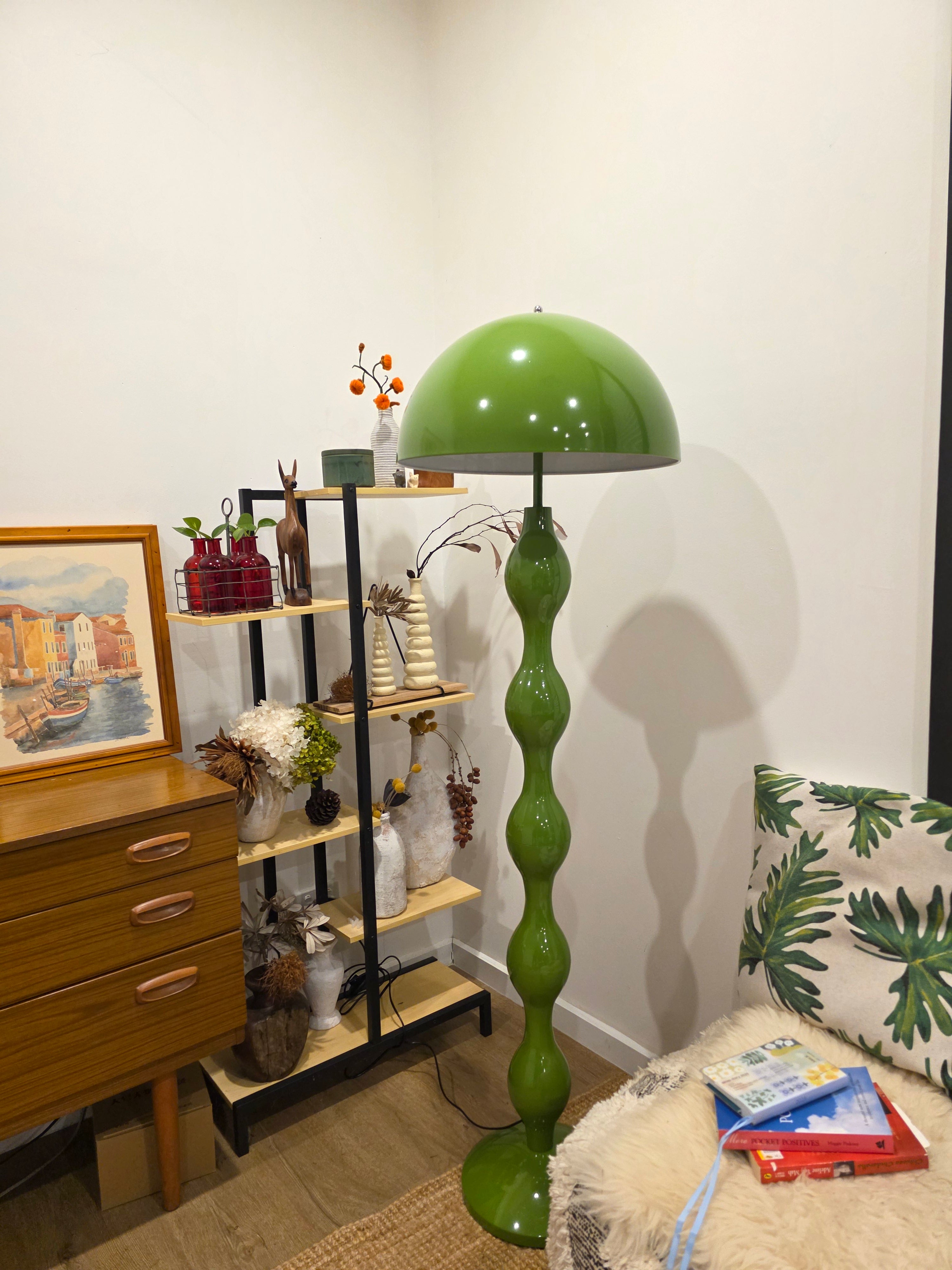 Dori Wavy Mushroom Floor Lamp in Olive Green with sculptural wavy base on a stand with decorative items in a room setting