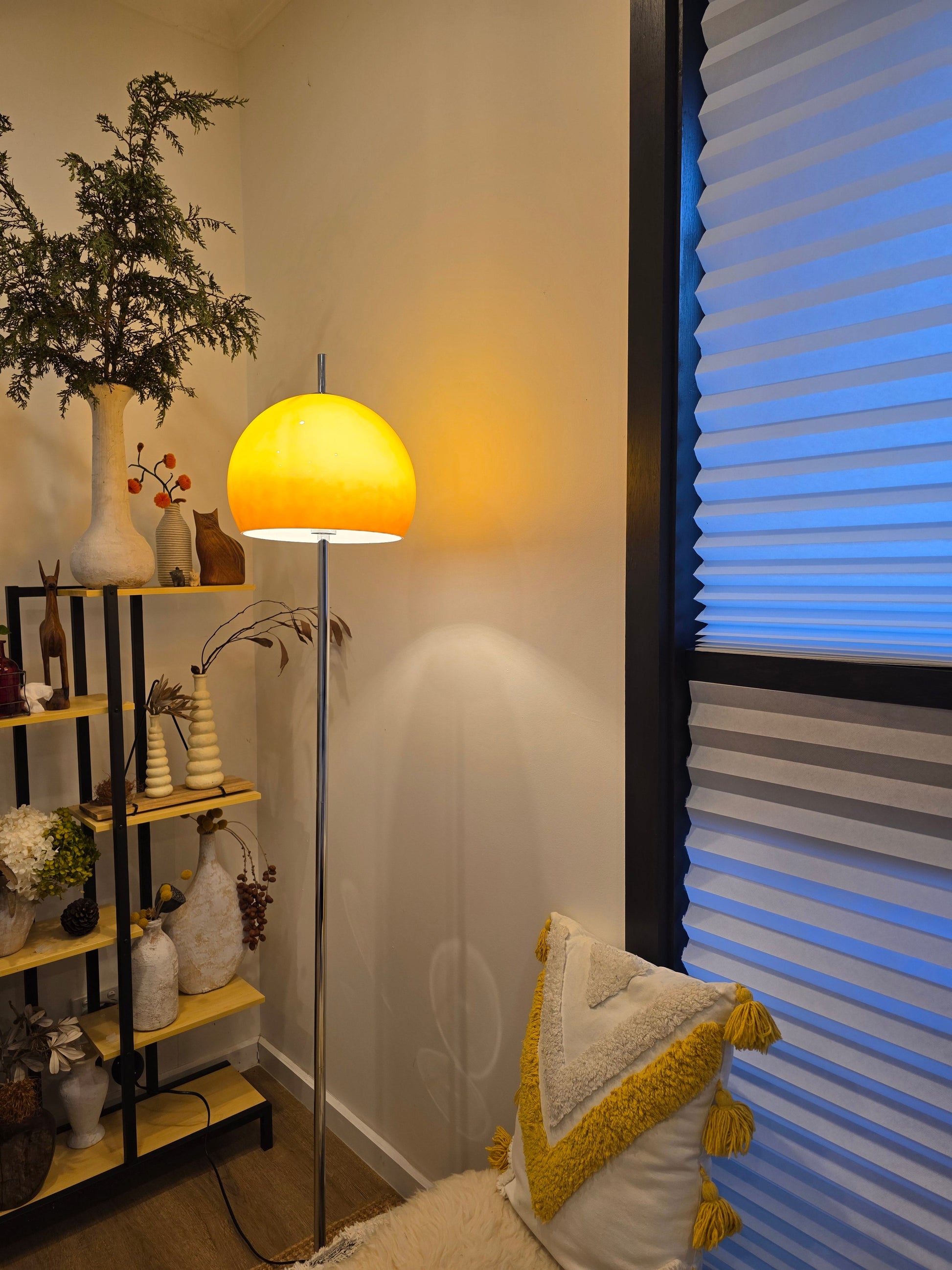  Living room with a Olivia Mushroom Bauhaus lamp, plants, and decorative pillows on a sofa.