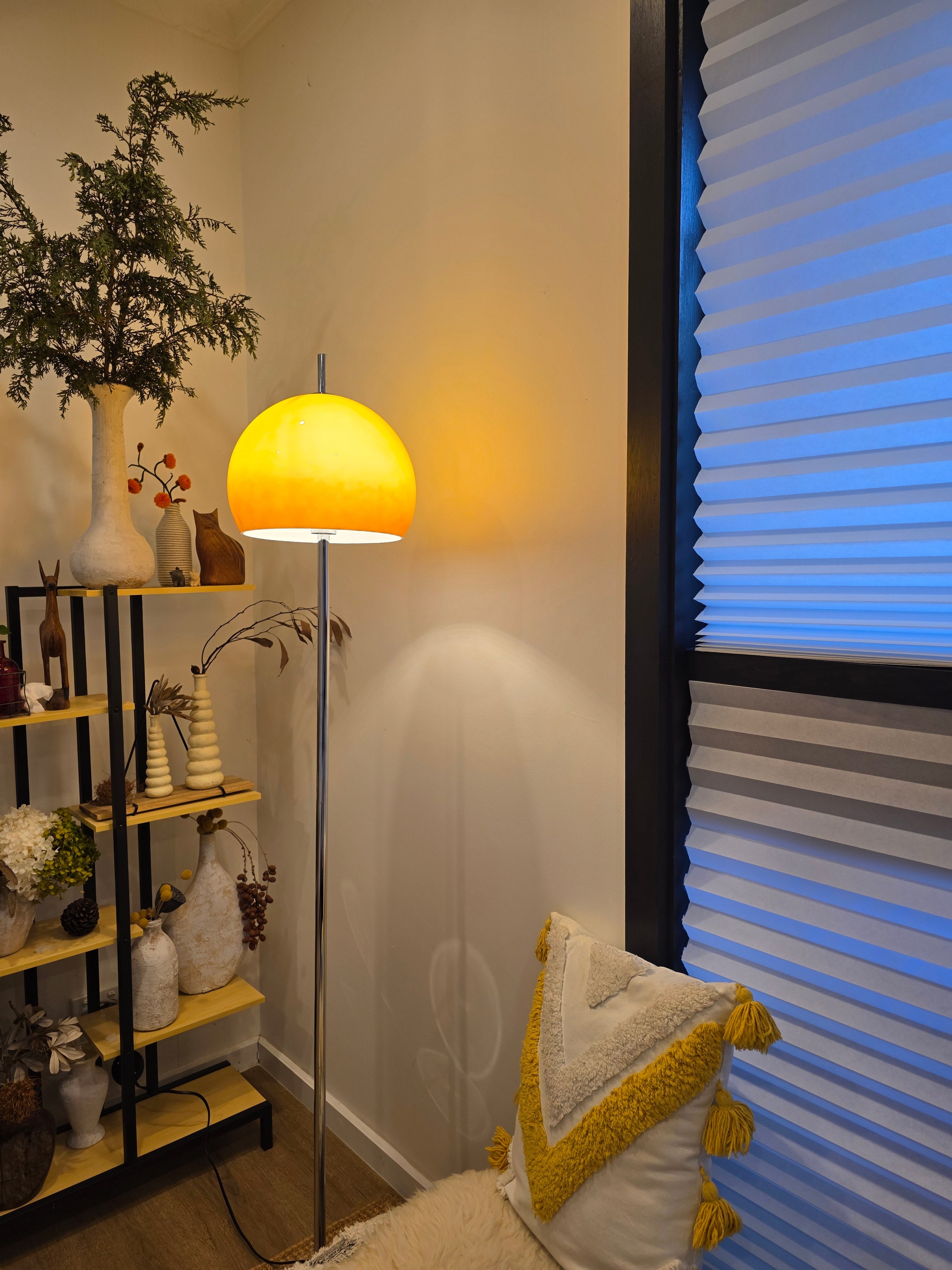  Living room with a Olivia Mushroom Bauhaus lamp, plants, and decorative pillows on a sofa.
