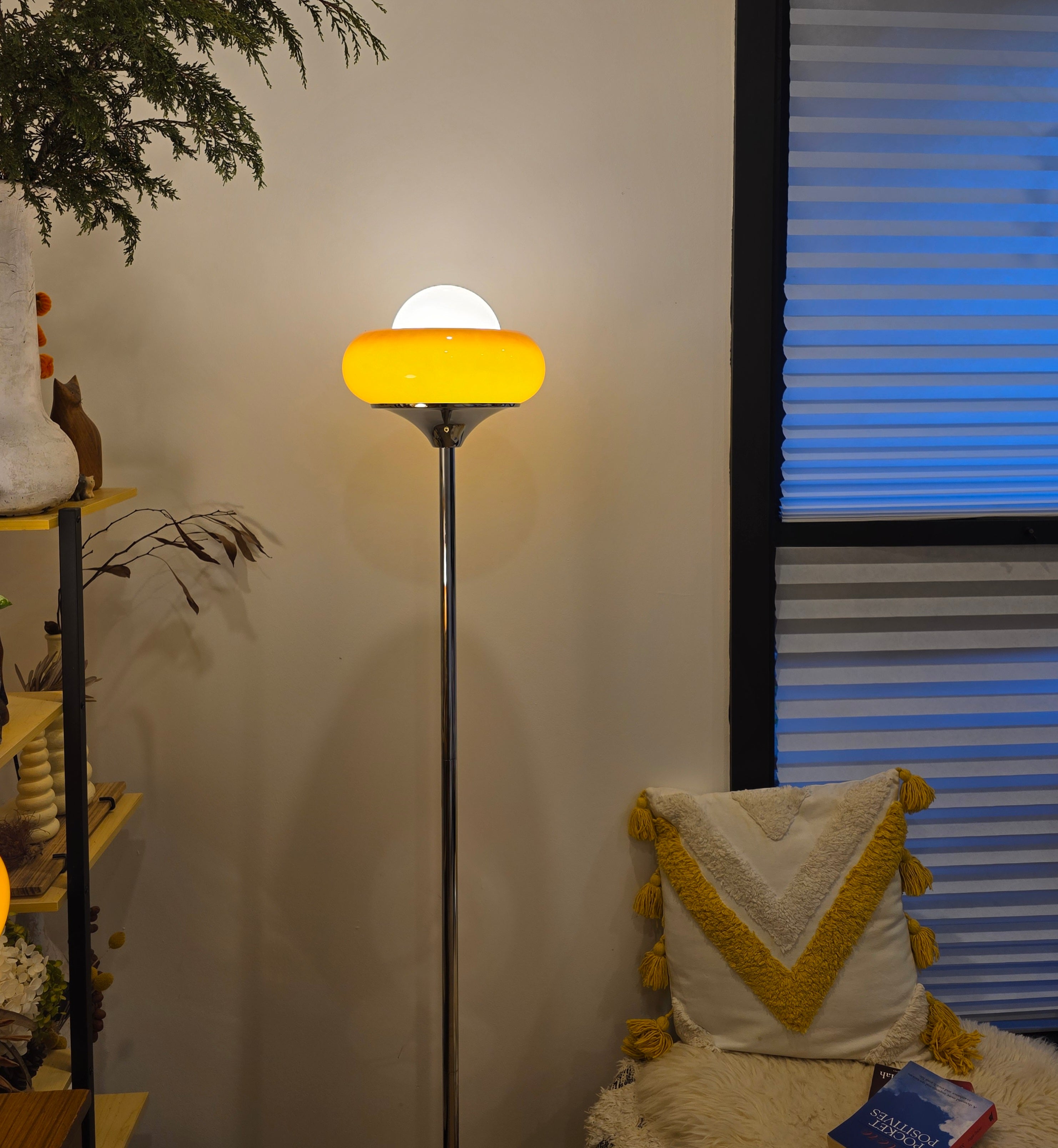 Egg Tart Floor Lamp with orange dome glass shade and white globe center in a room with a window and decorative pillow.