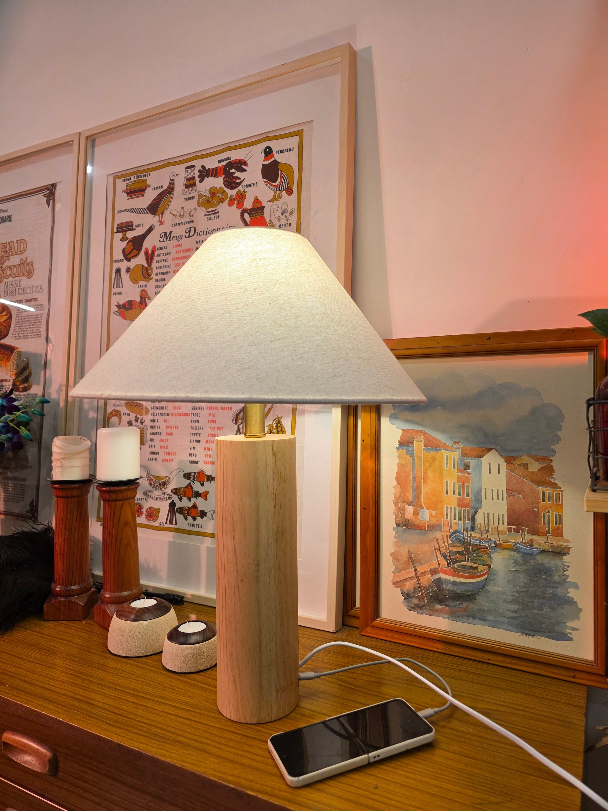 Teak wood table lamp with touch brass button and Type-C port on a desk with framed pictures and a smartphone in the background
