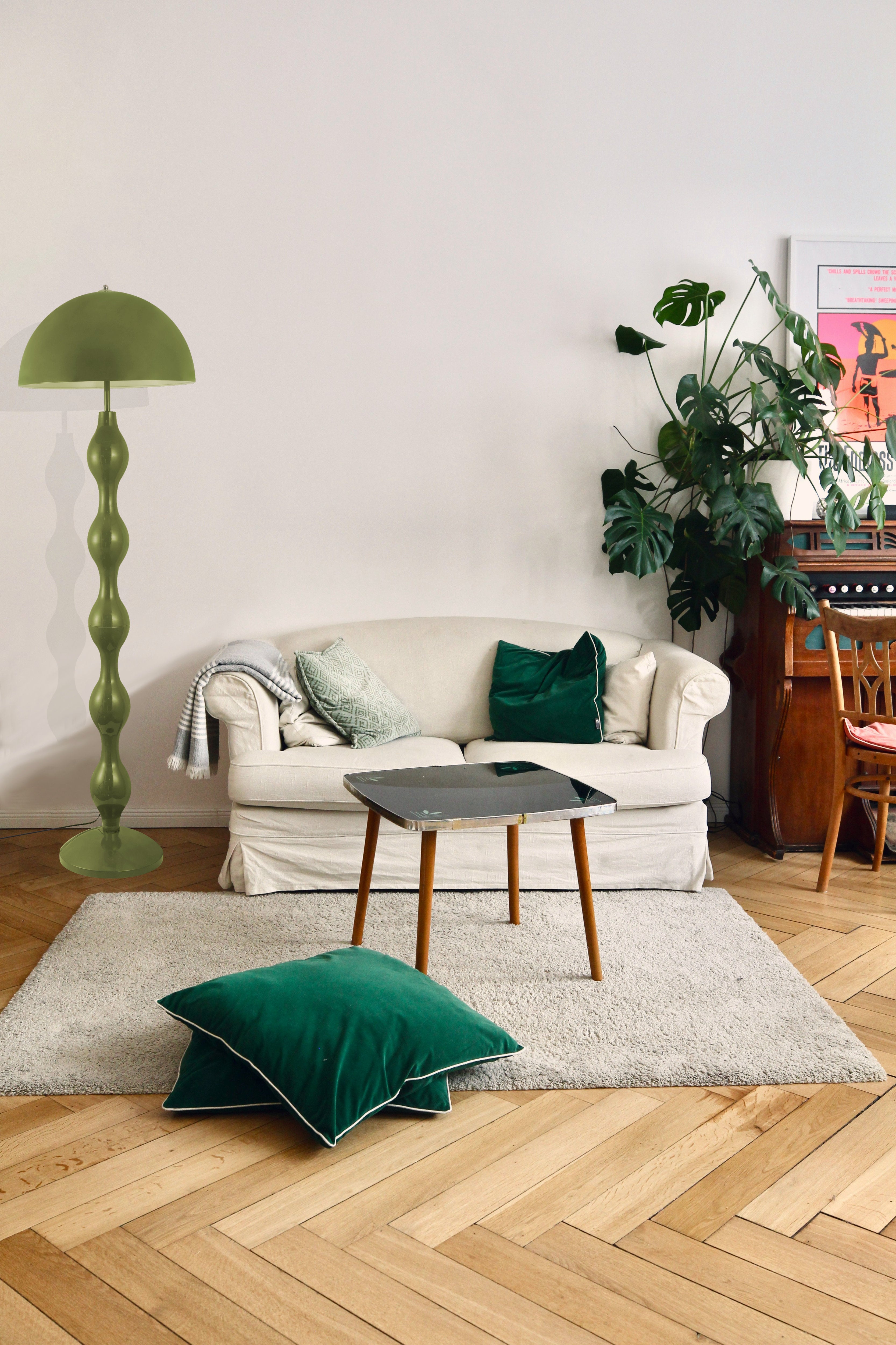 Living room with a white sofa, Dori Wavy Mushroom Floor Lamp in Olive Green with sculptural wavy base, and decorative pillows on a wooden floor.