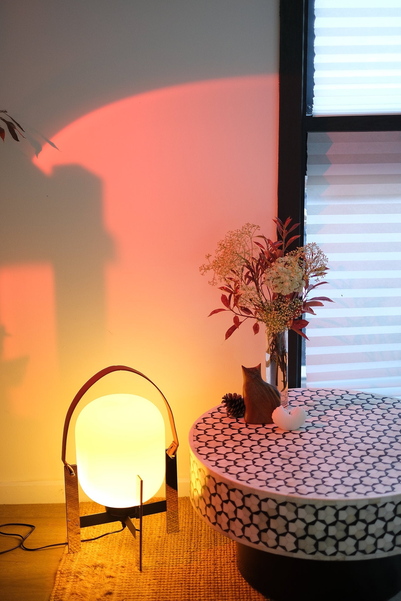 Small round table with decorative items next to Alix Cesta Metalica Basket Lamp with chrome frame and opal glass globe