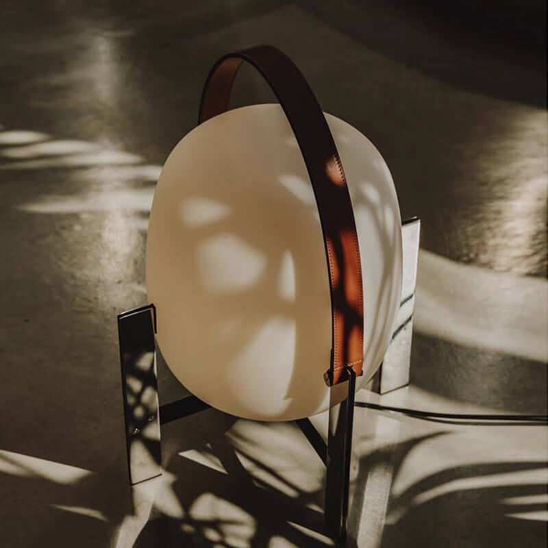 Alix Cesta Metálica Basket Lamp with chrome legs and frosted glass on a reflective surface with shadows