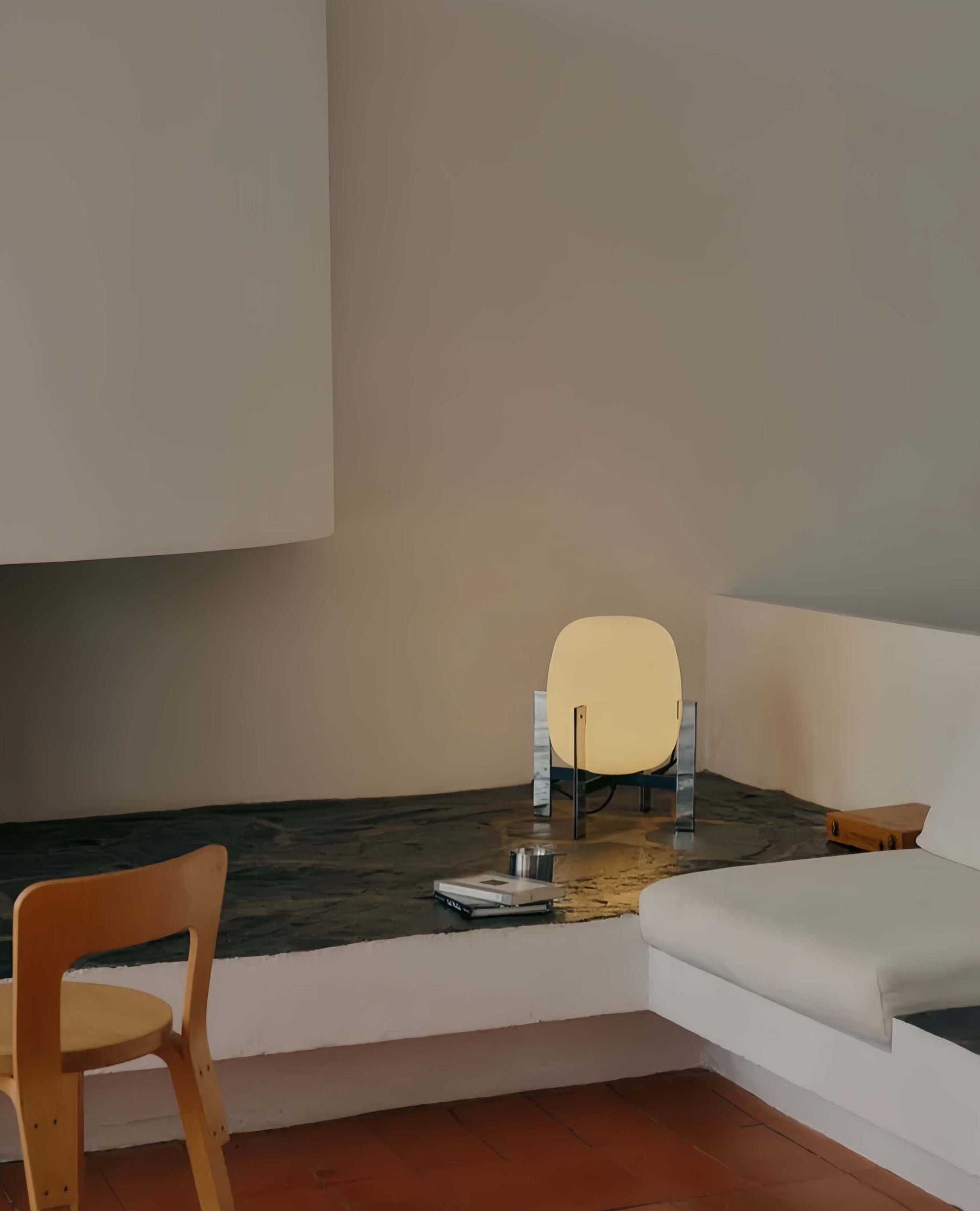 Modern interior with a wooden chair, and a Alix Cesta Metálica Basket Lamp with chrome legs and frosted glass.