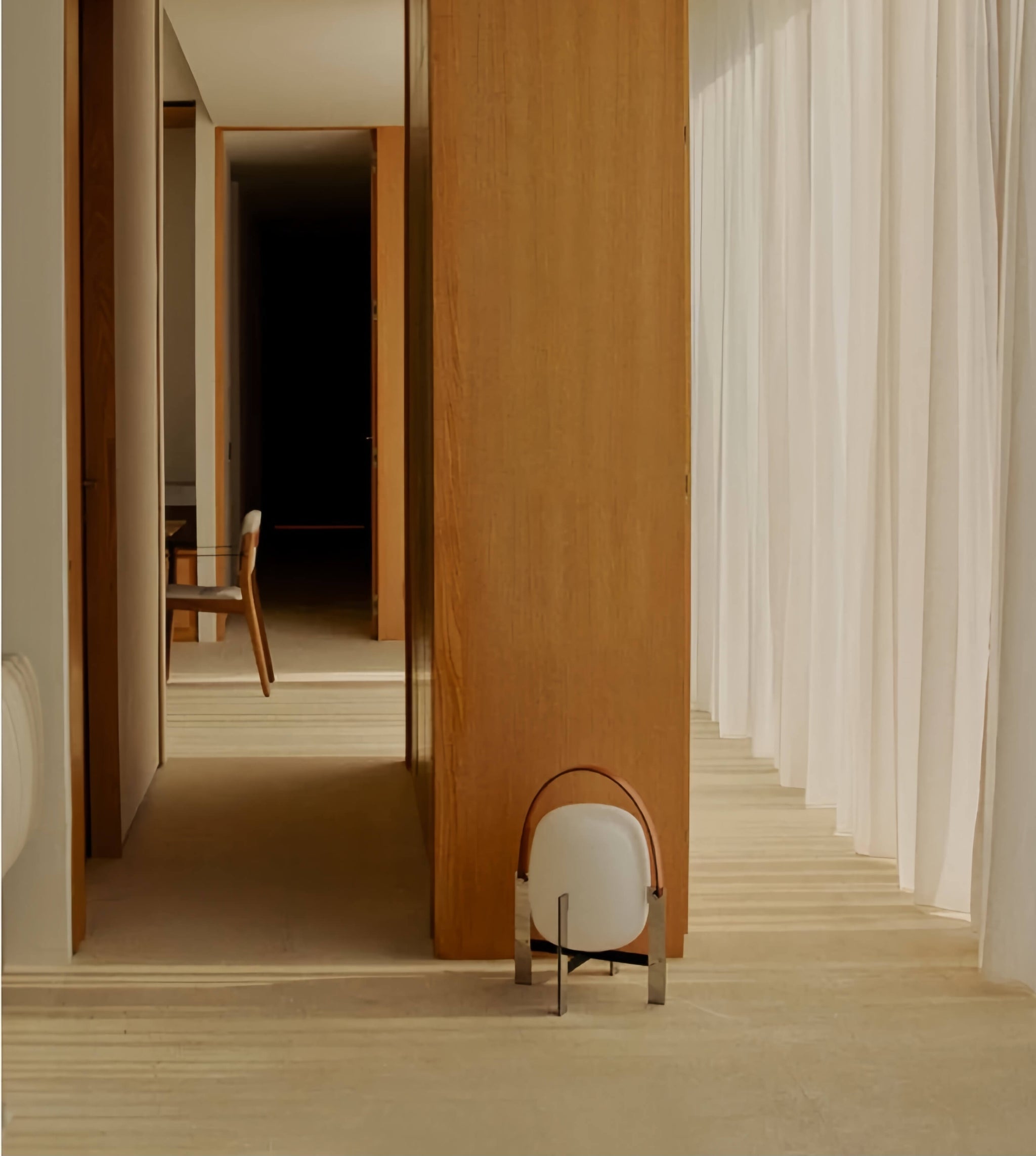 Modern interior with wooden partition, chair, white curtain and Alix Cesta Metálica Basket Lamp with chrome legs and frosted glass on the floor