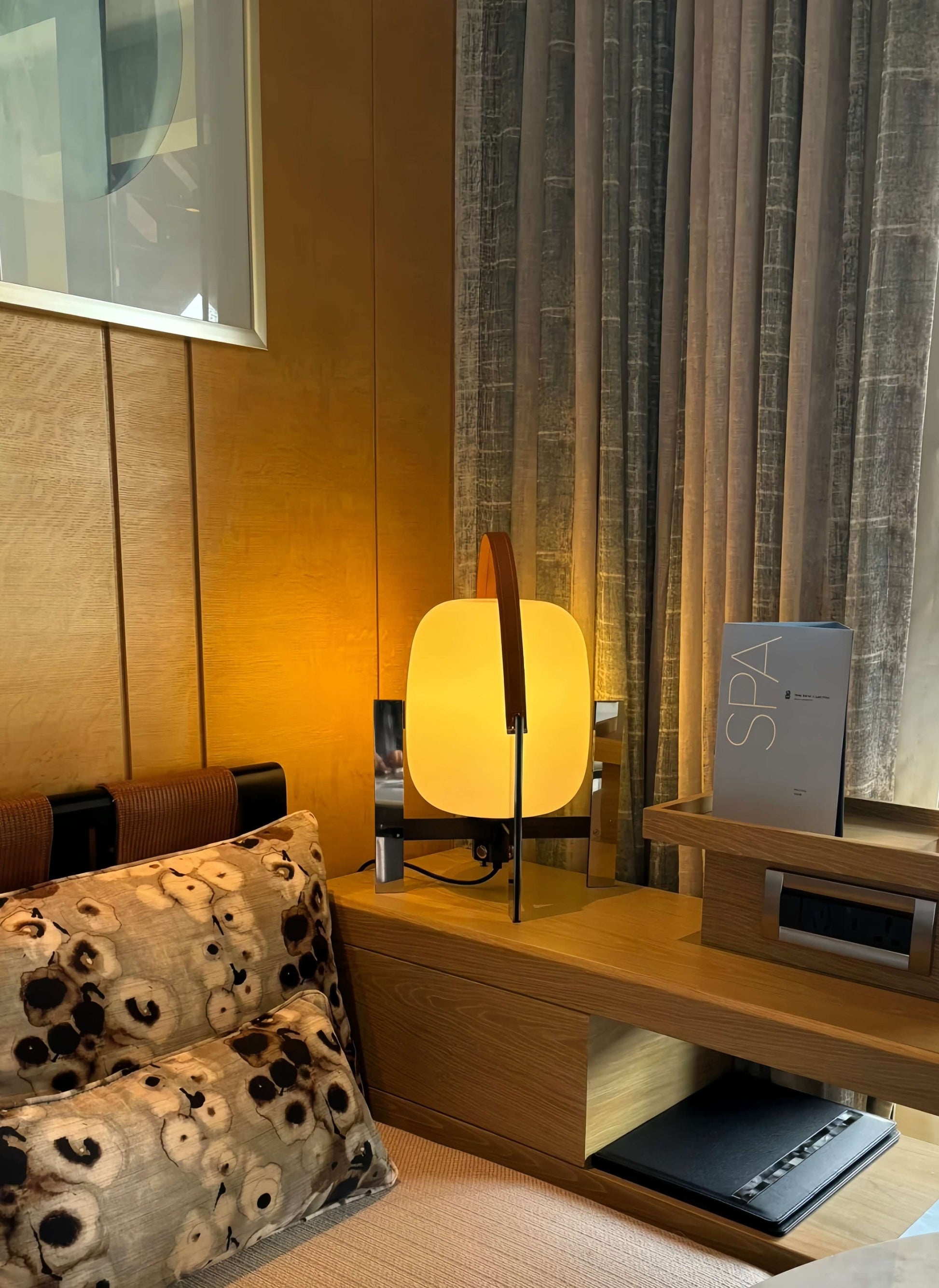 Alix Cesta Metálica Basket Lamp with chrome legs and frosted glass  on a wooden nightstand next to a bed with a floral pillow