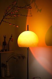 Mushroom Bauhaus floor lamp casting a warm glow in a dimly lit room with decorative elements.
