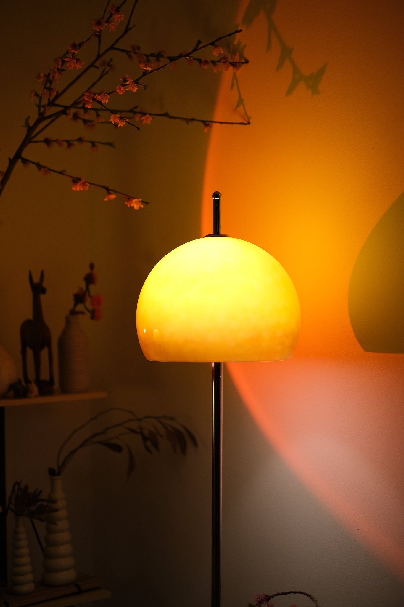 Mushroom Bauhaus floor lamp casting a warm glow in a dimly lit room with decorative elements.