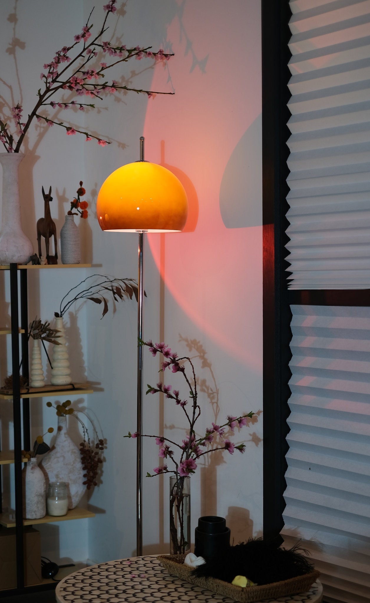 Olivia Mushroom Bauhaus Yellow lampshade on a stand with decorative items and flowers against a textured wall.