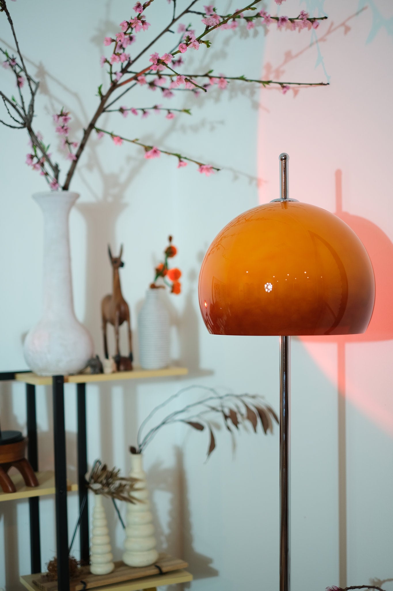 Olivia Mushroom Bauhaus Orange lampshade in a room with decorative elements and a light blue wall.