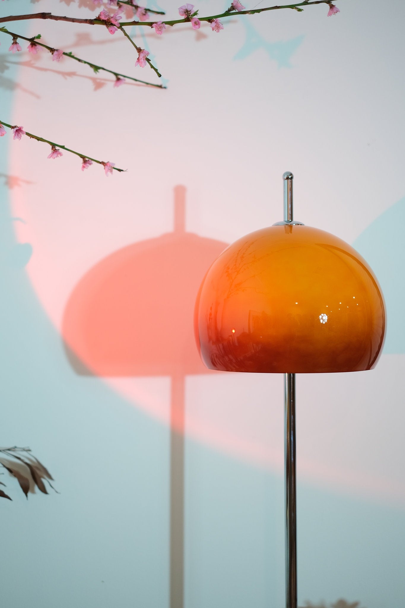 Olivia Mushroom Bauhaus Orange lampshade on a stand with cherry blossoms in the background