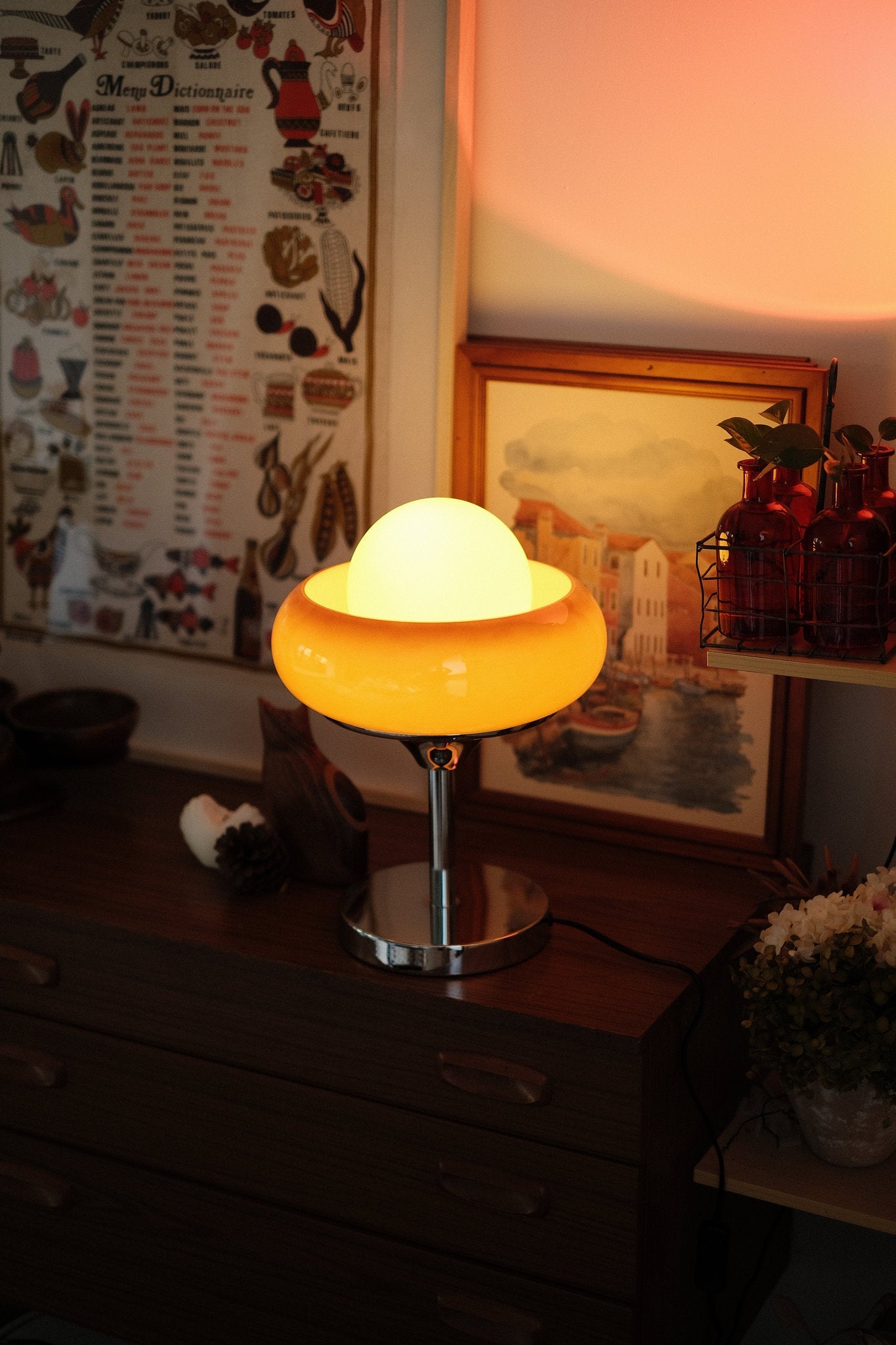 Vintage-style Every Egg Tart retro table lamp  – sculptural glass for cozy spaces on a wooden surface with a warm glow, surrounded by decorative items.