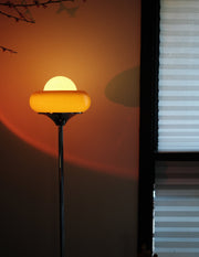 Egg Tart Floor Lamp with orange dome glass shade and white globe center with a yellow glass shade casting a shadow on a wall.