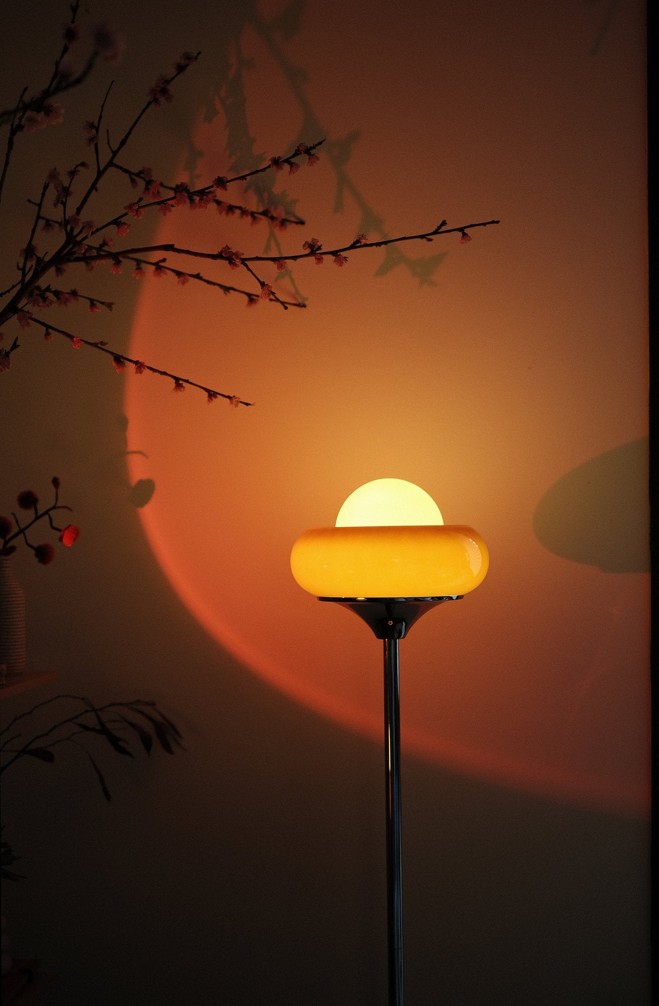 Egg Tart Floor Lamp with orange dome glass shade and white globe center casting a warm glow with a sunset or sunrise in the background