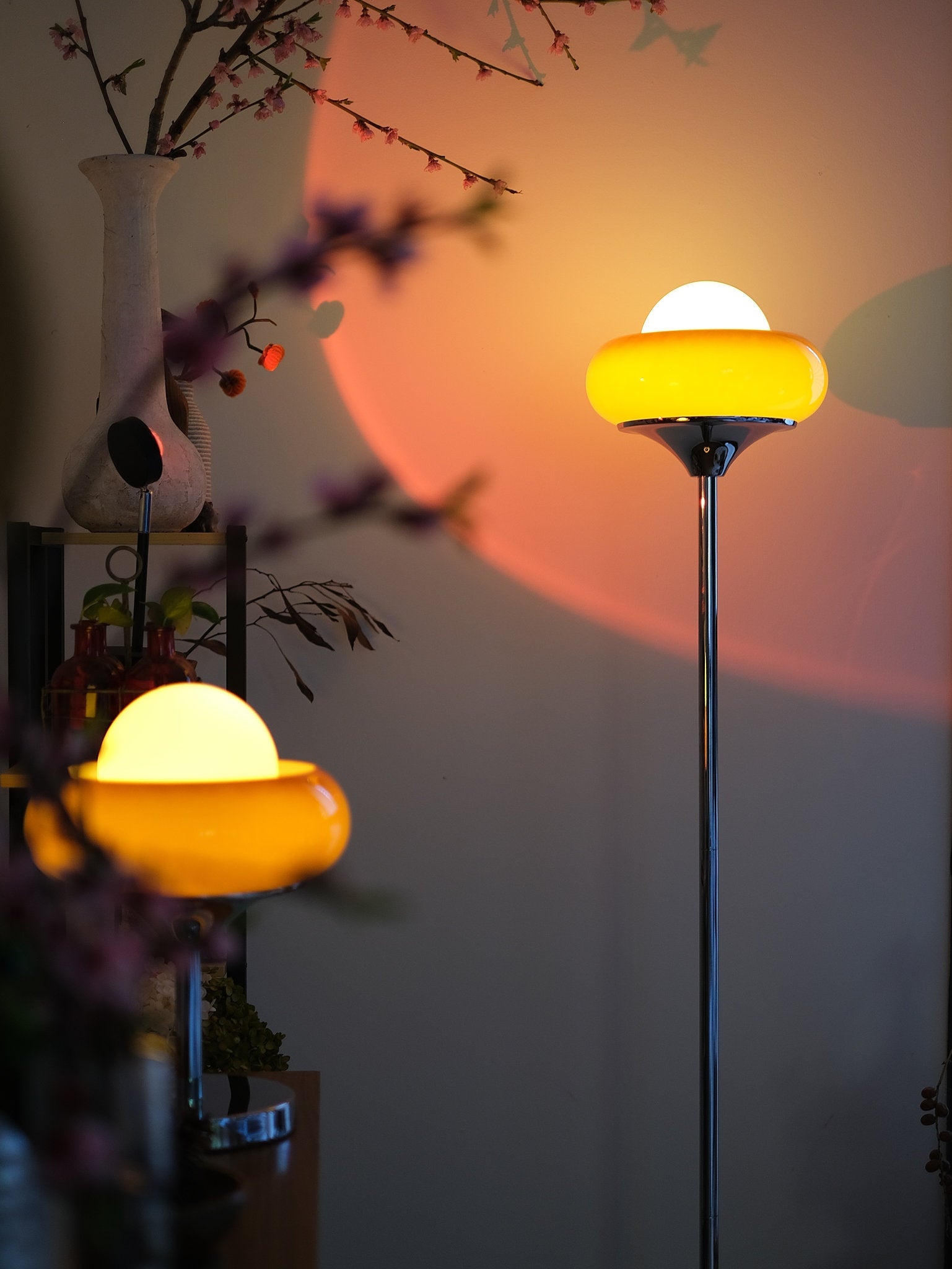 Avery Egg Tart Floor and Table Lamp Set with curved glass dome shades in orange and white casting shadows on a wall in a dimly lit room.