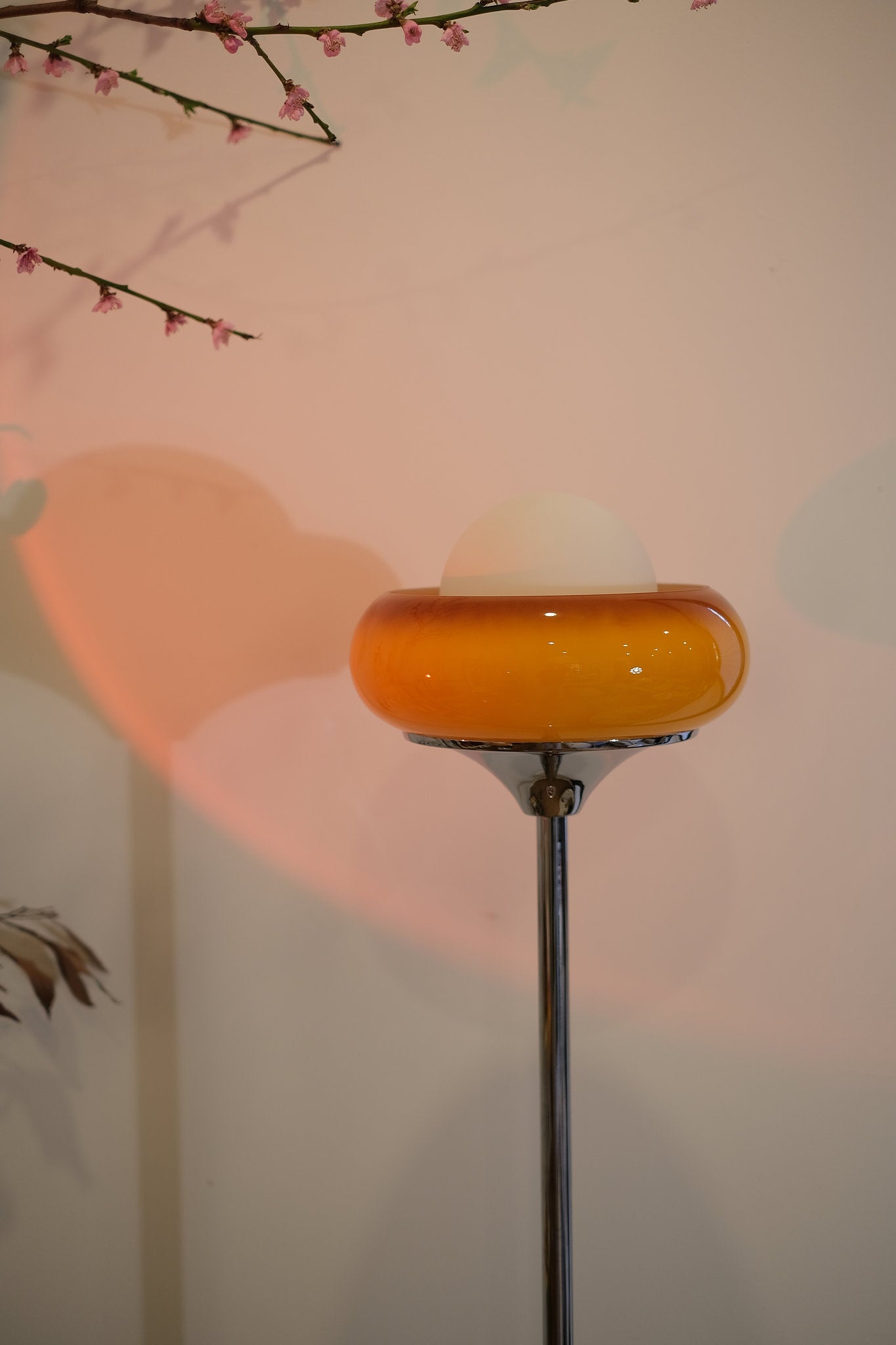 70s inspired Egg Tart lamp styled as cozy corner lighting with a yellow glass shade against a light pink wall.