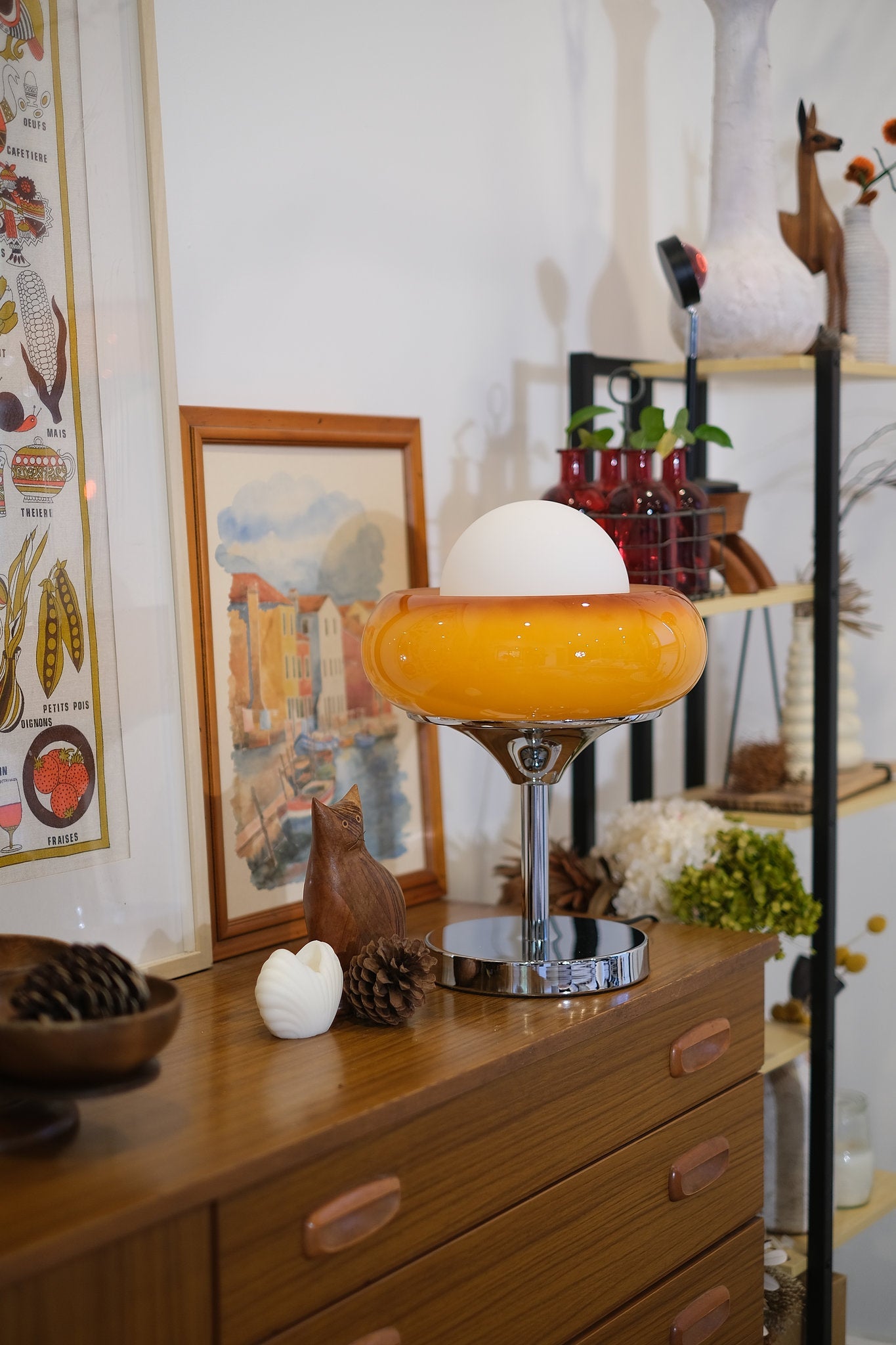 Vintage-style interior with a wooden dresser, Egg Tart Table Lamp with orange dome glass shade and white inner globe, and decorative items.
