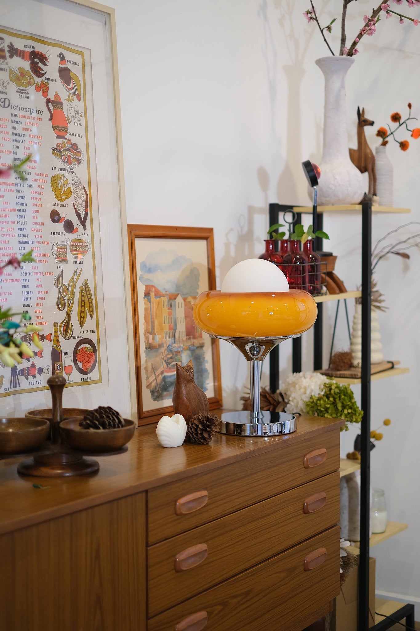 Vintage-style room with wooden dresser, Egg Tart Table Lamp with orange dome glass shade and white inner globe, and decorative items.