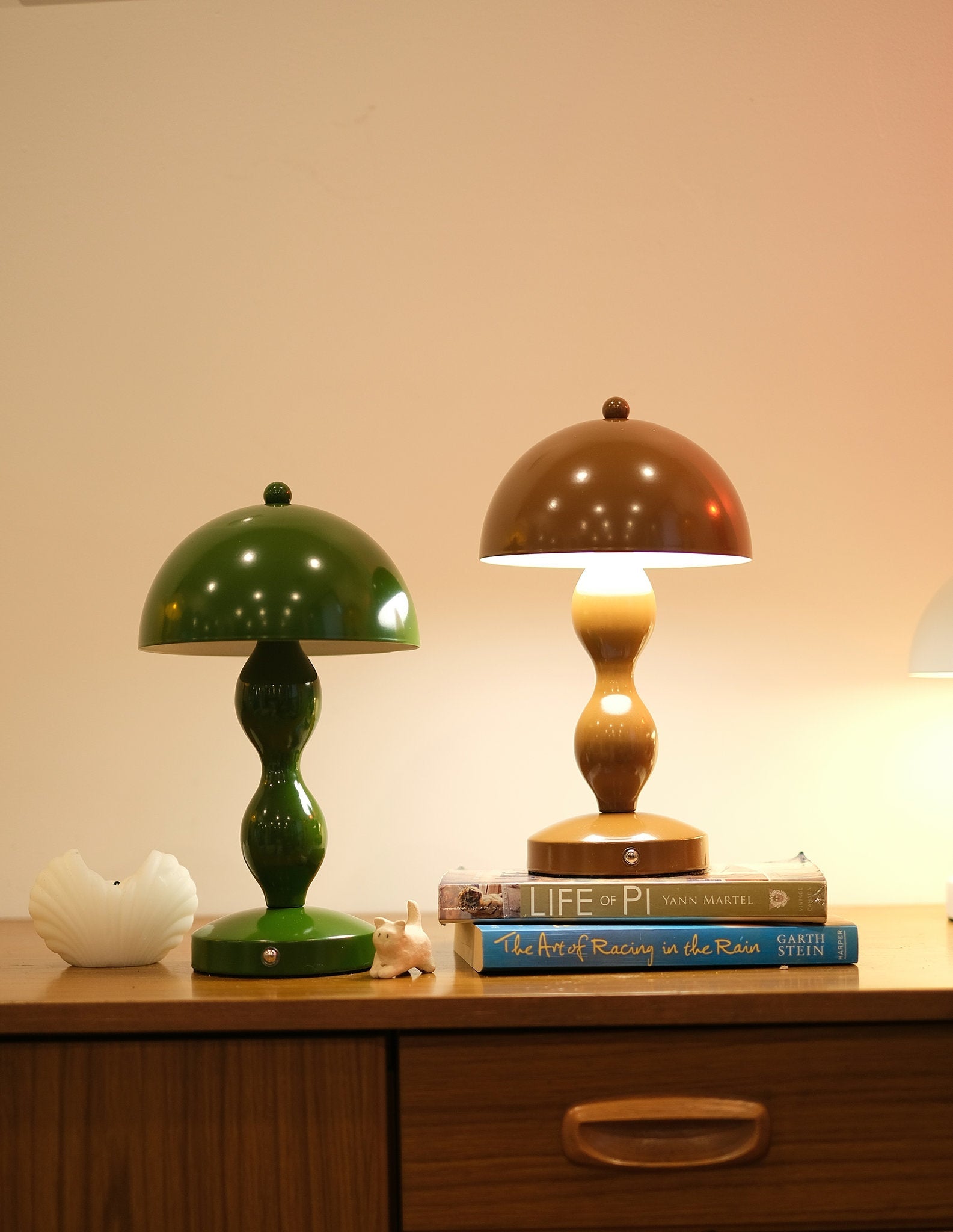 Dori Portable LED Table Lamp in Olive Green and Mocha Brown on wooden table on a wooden surface with books underneath, against a neutral background.