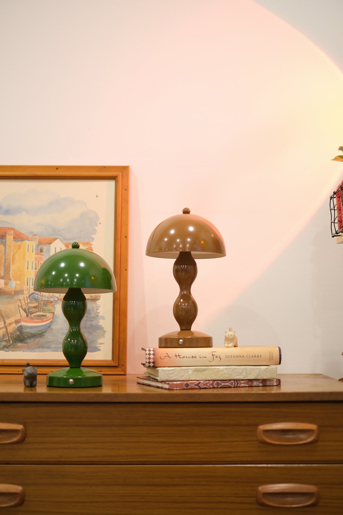 Retro mushroom lamp glowing softly in modern interior décor on a wooden dresser with a framed painting in the background.