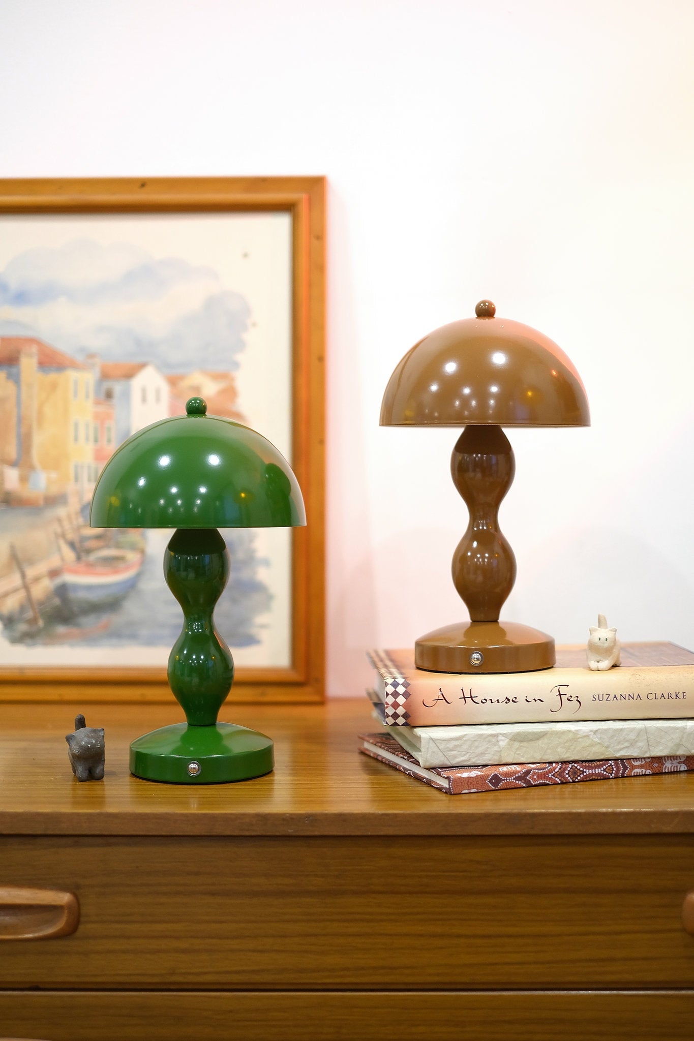 Retro mushroom lamp glowing softly in modern interior décor on a wooden surface with a framed painting in the background.