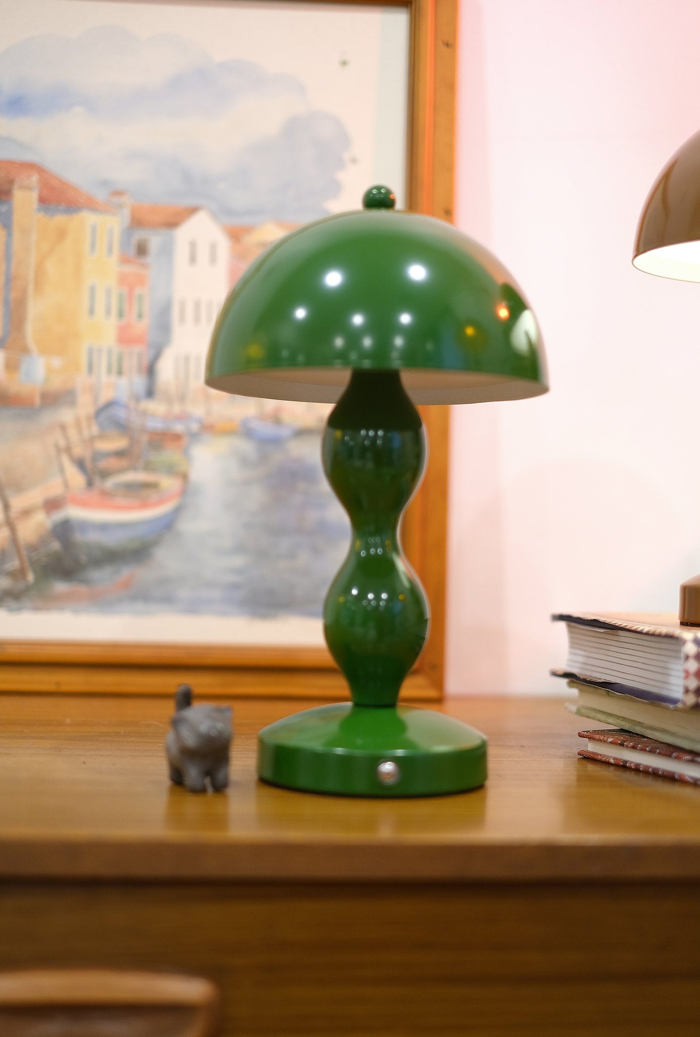 Dori LED lamp close-up showing touch switch base on a wooden surface with a painting in the background