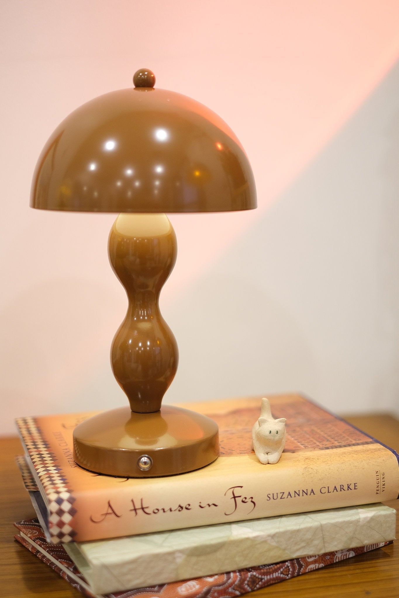 Dori LED lamp close-up showing touch switch base on a stack of books with a blurred background