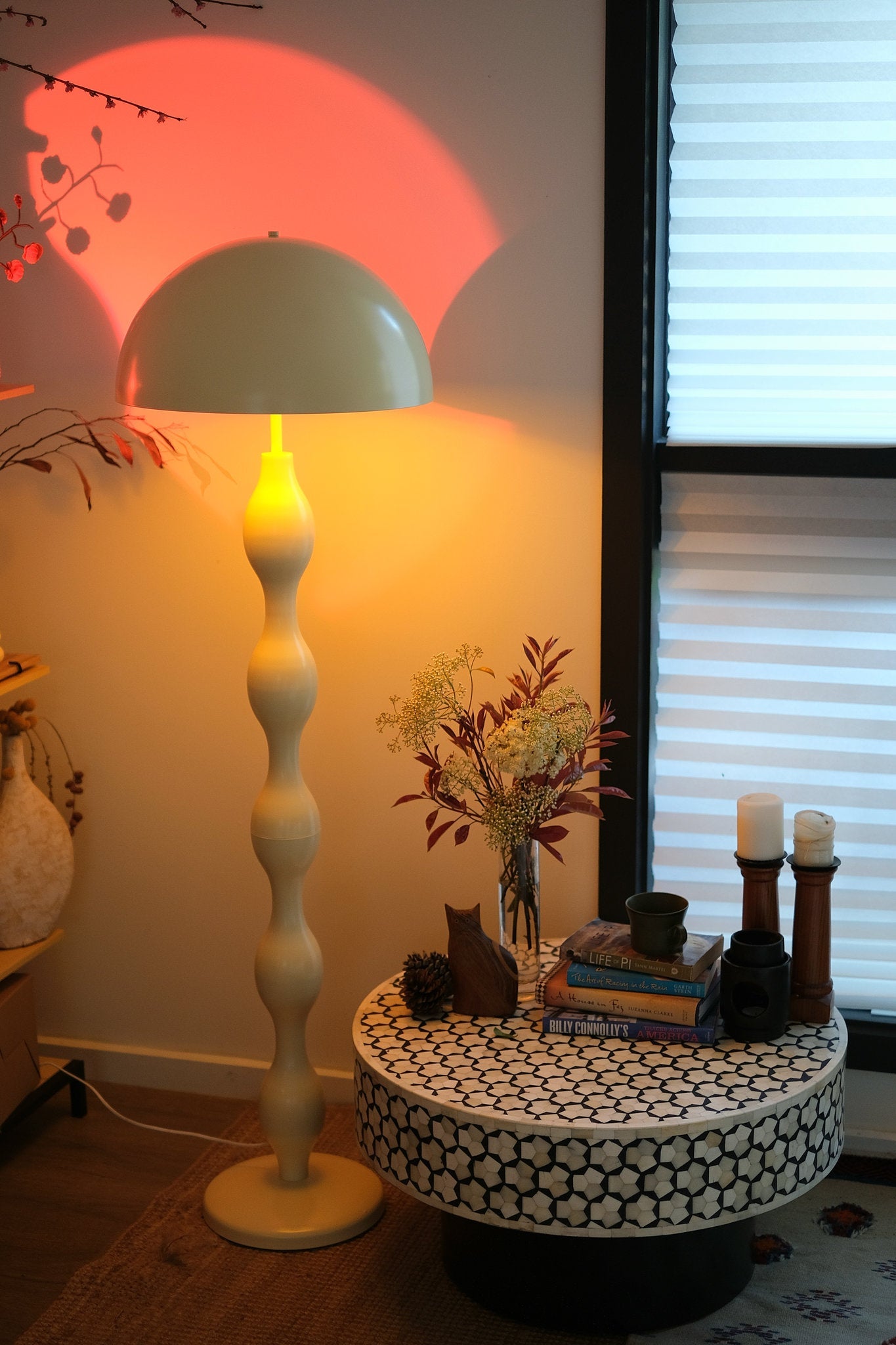 Decorative table with candles and a vase next to a Retro modern mushroom lamp with wavy sculptural base in butter yellow
