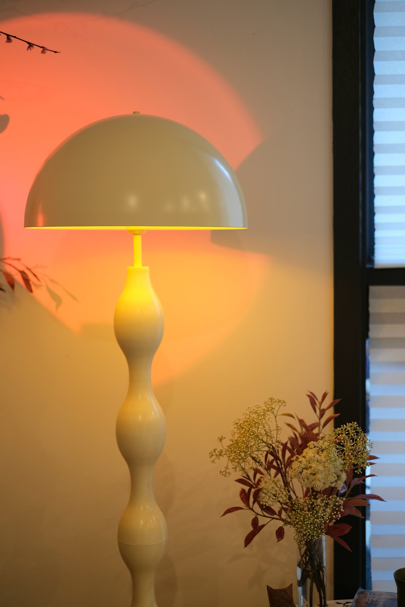 Funky butter yellow mushroom lamp styled in a modern living room against a wall with a decorative plant.