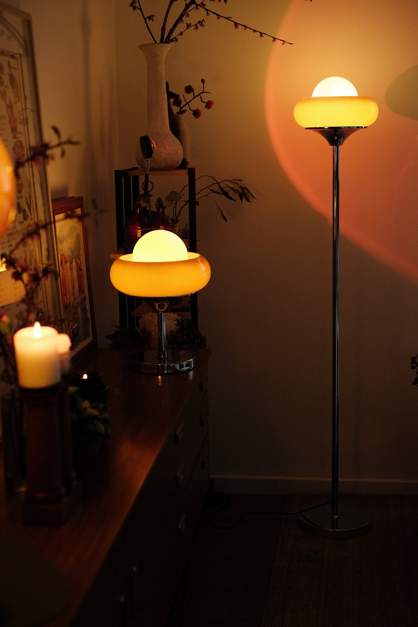 Two illuminated Bauhaus-inspired Egg Tart Lamp set casting soft ambient glow in living room décor with a candle and decorative items.