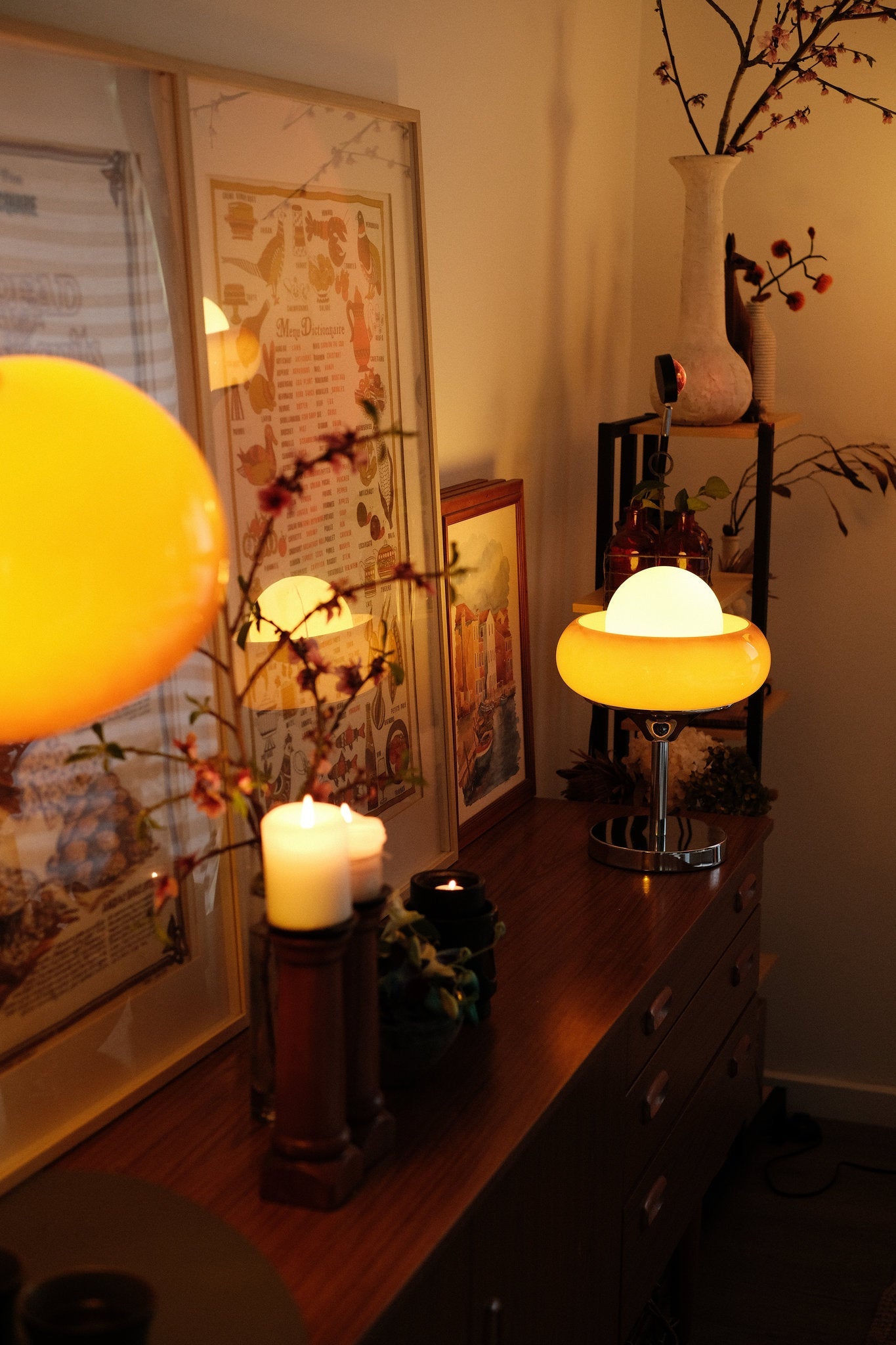 Bauhaus-inspired Egg Tart Table Lamp casting soft ambient glow in living room décor and candles on a wooden surface with decorative elements