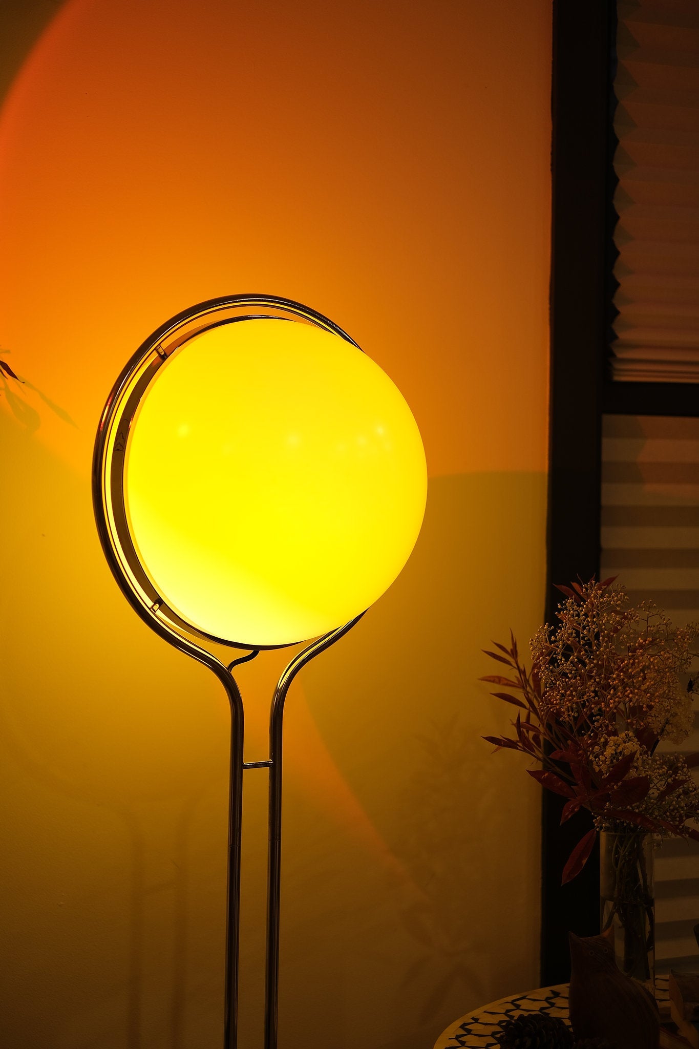Yellow lamp shaped like a tennis ball on a stand against an orange wall， Garreau Globe Floor Lamp Bauhaus Replica Chrome Stand