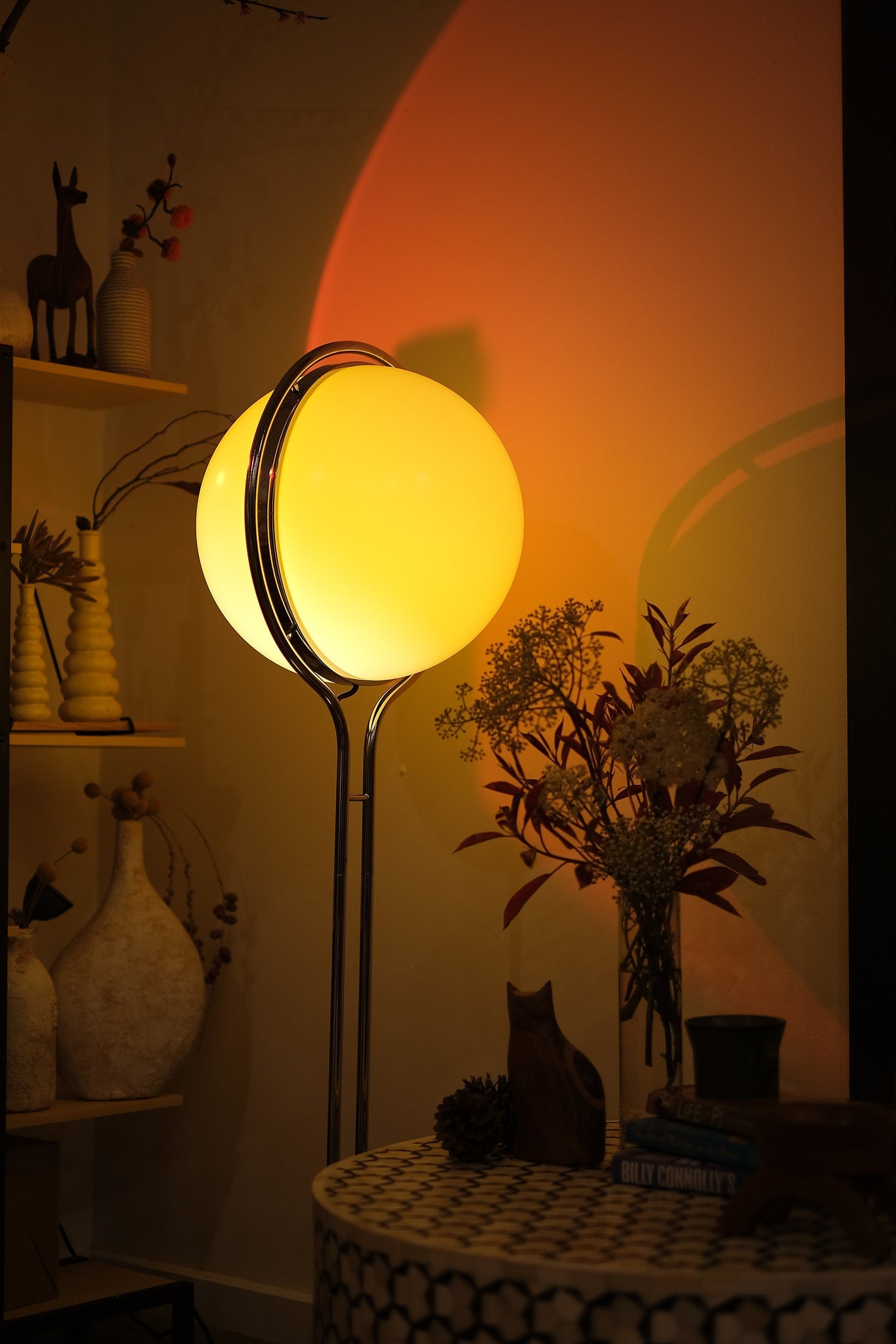 Floor lamp with a warm glow in a dimly lit room with decorative items. Garreau Globe Floor Lamp Bauhaus Replica Chrome Stand