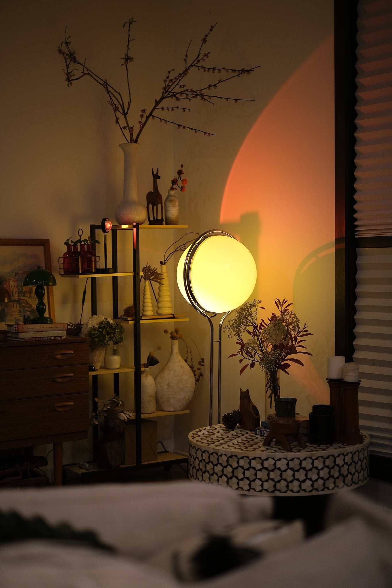 Room interior with a Garreau Globe Floor Lamp Bauhaus Replica Chrome Stand, shelves, and decorative items. 