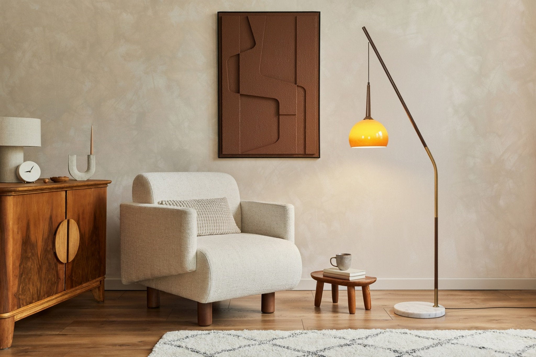 Hulusi Hanging Floor Lamp with walnut stand and gradient orange glass shade next to a cream arm chair
