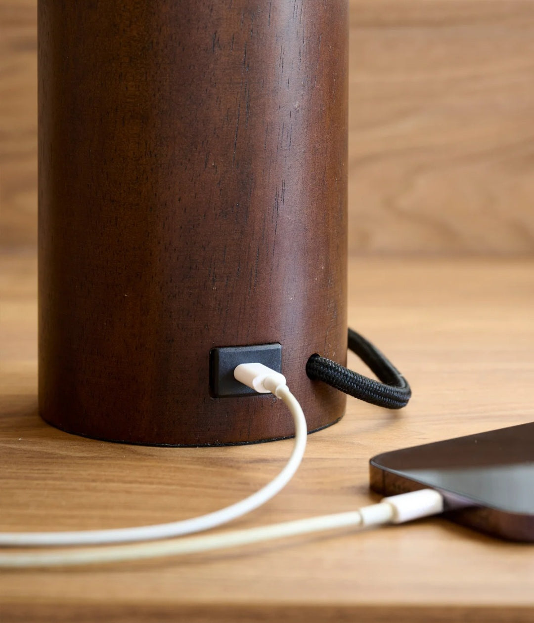 Brown cylindrical device with a power cord plugged into it on a wooden surface