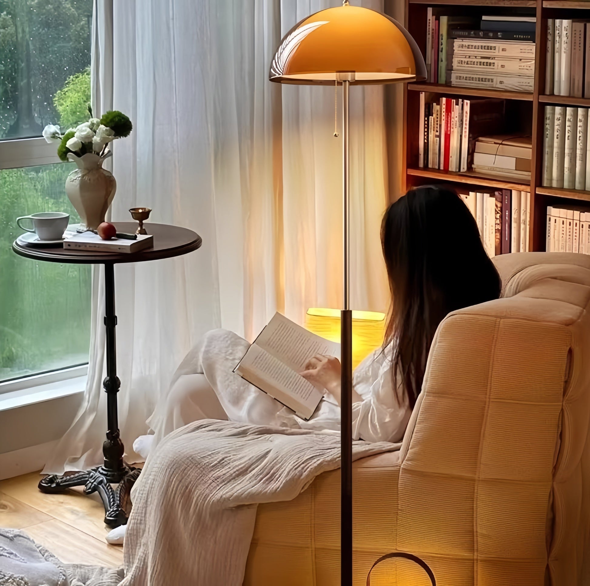 Woman reading a book on a couch in a cozy living room with a side table and Coby+ Mushroom Bauhaus Floor Lamp Orange with Pull Chain.