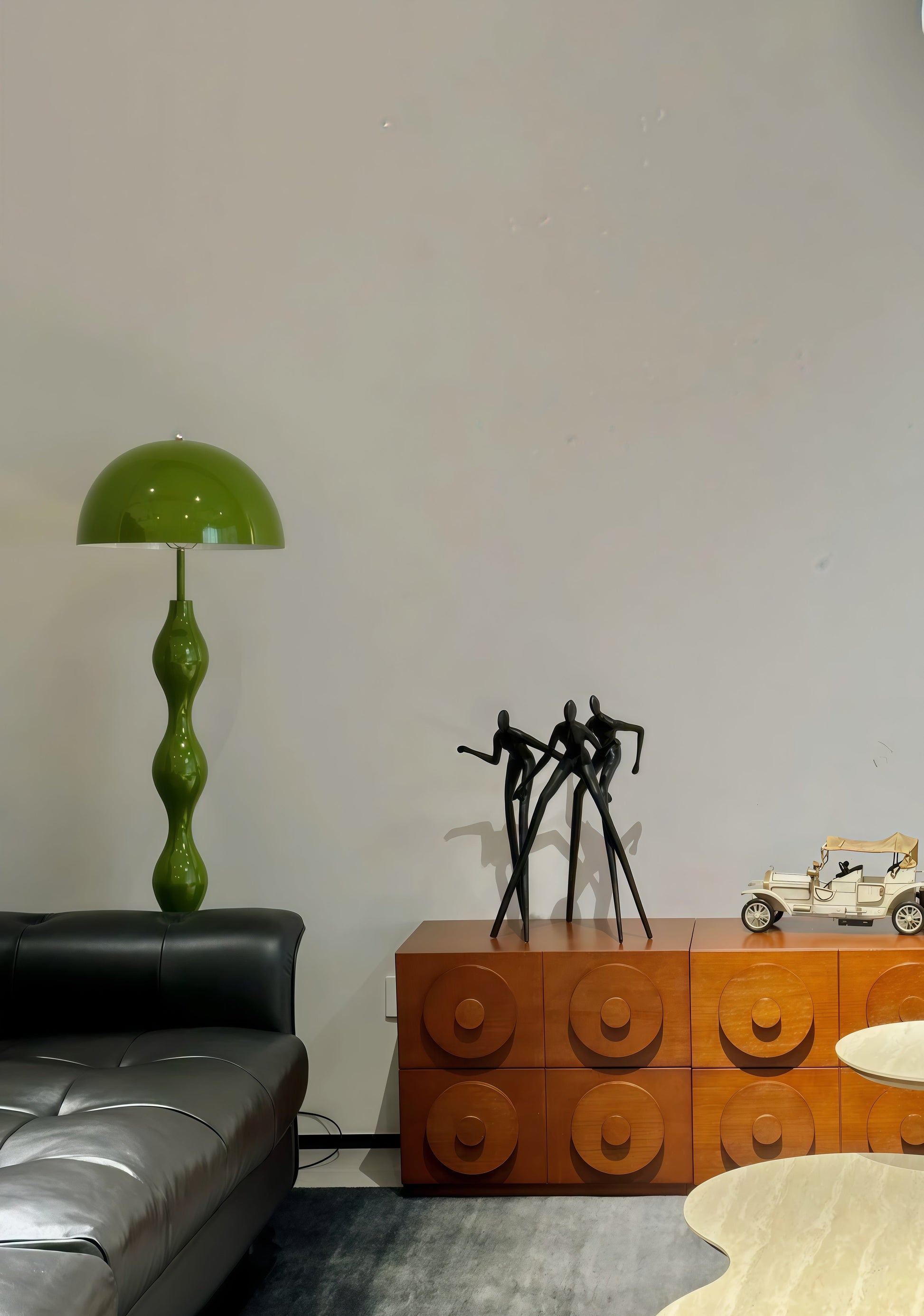 Living room with a Dori Wavy Mushroom Floor Lamp in Olive Green with sculptural wavy base, wooden cabinet, and black sculpture.